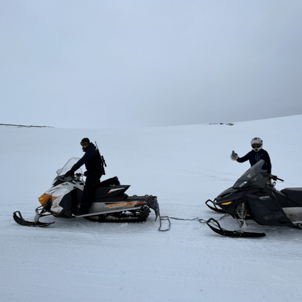 Friends of Katrin collaborate to tow a broken-down snowmobile back into town. Iqaluit, May 2023.